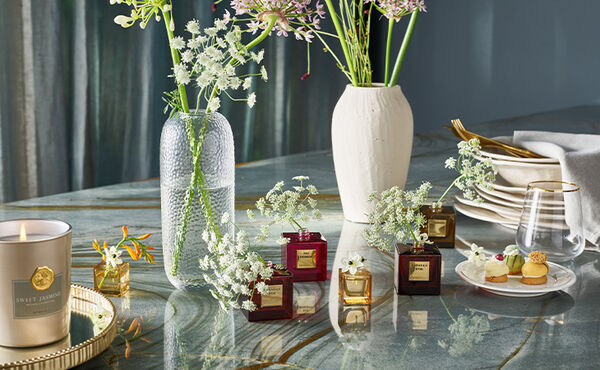 Repurposed Rituals perfume bottles used as miniature vases with delicate white flowers.